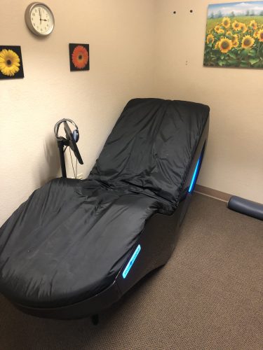Relaxing treatment room featuring a HydroMassage chair and sunflower wall décor at Spine & Injury Center of Grand Junction