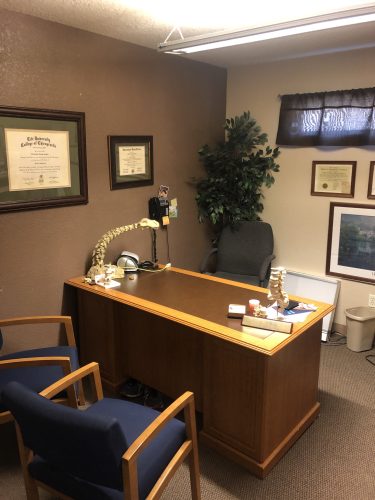 Consultation office at Spine & Injury Center of Grand Junction featuring anatomical spine models and framed professional credentials