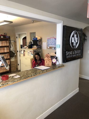 Front desk of Spine & Injury Center of Grand Junction with staff assisting patients in a professional chiropractic setting