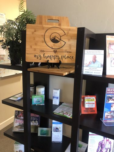 Multi-tiered bookshelf with nutritional supplements, patient brochures, and wellness guides at Spine & Injury Center of Grand Junction